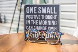 http://木牌標語：One%20small%20positive%20thought%20in%20the%20morning%20can%20change%20your%20whole%20day，前方放著眼鏡